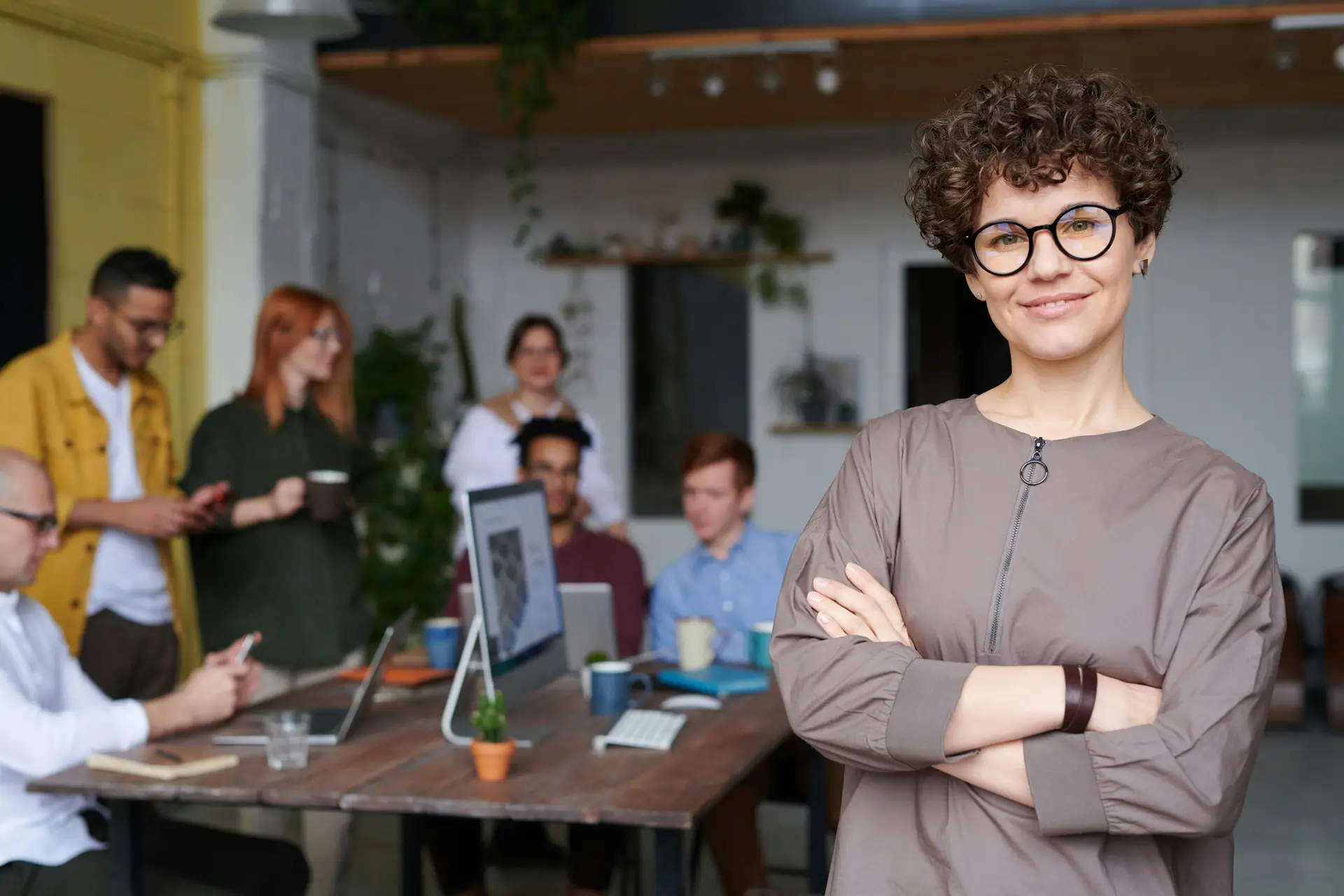 A female with glasses standing before a team of workers.