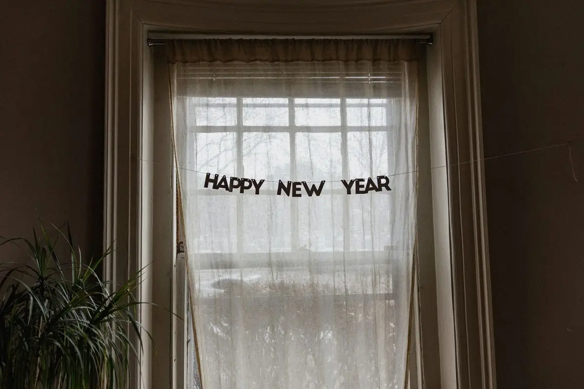 Happy New Year sign hanging in a curtained window.