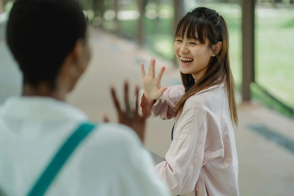 Two person waving at each other.