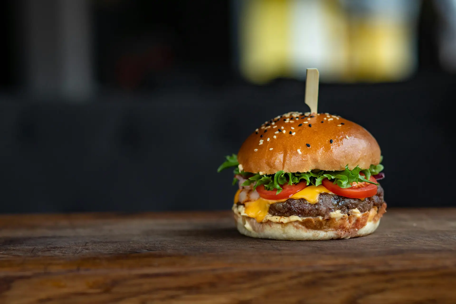A cheeseburger on a wooden surface.