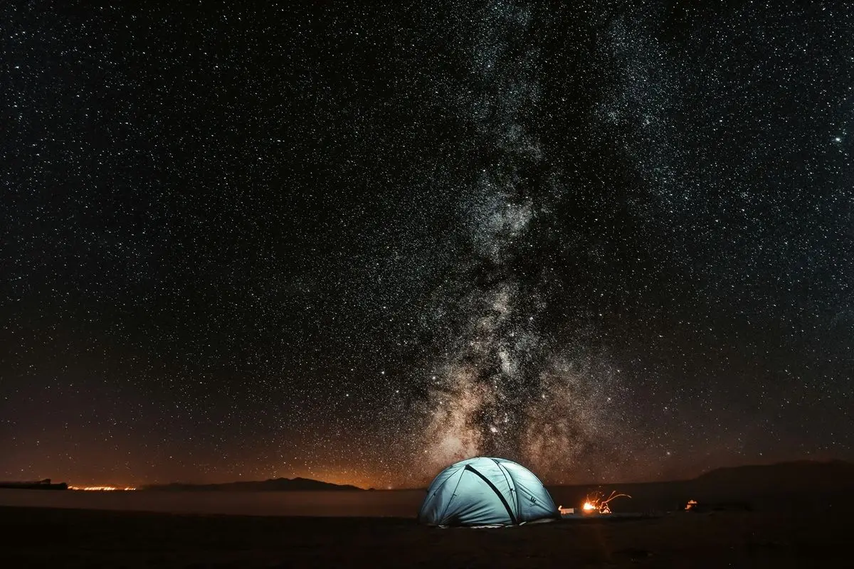 A blue tent in night time. The milkyway is visible.