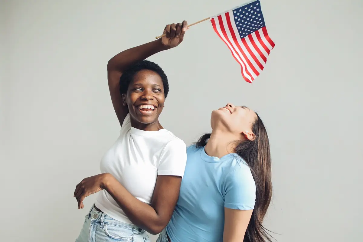 Two women joyfully celebrating with an American flag on Juneteenth.