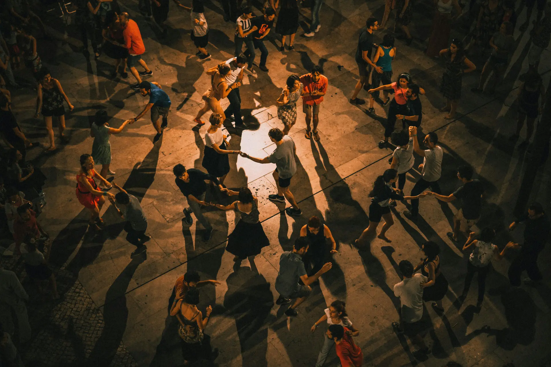 A group of people dancing in the night under lime light.