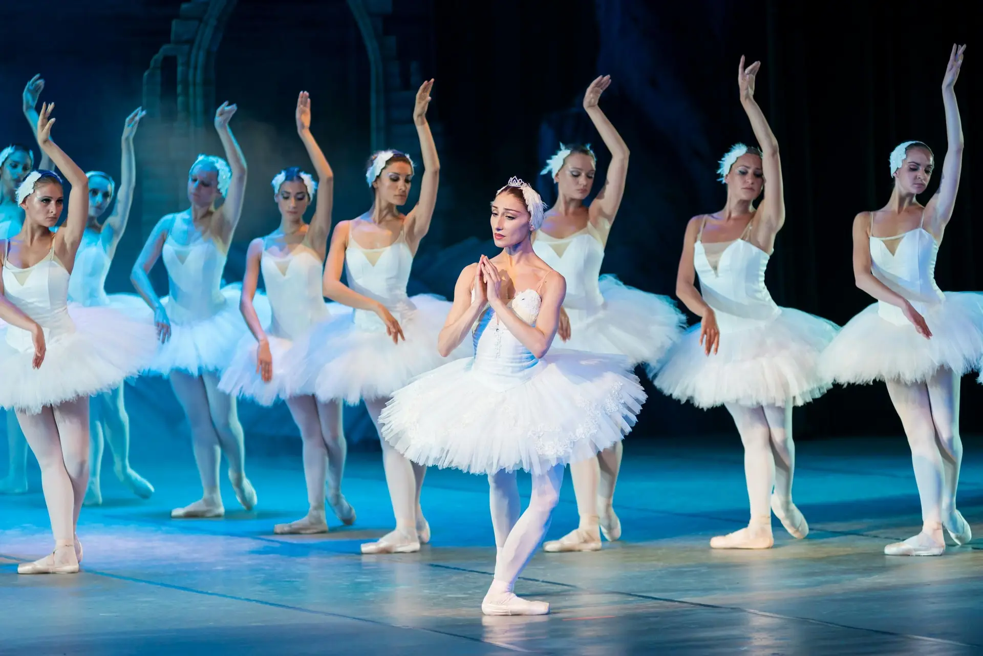 Bunch of women dressed in white are dancing ballet.