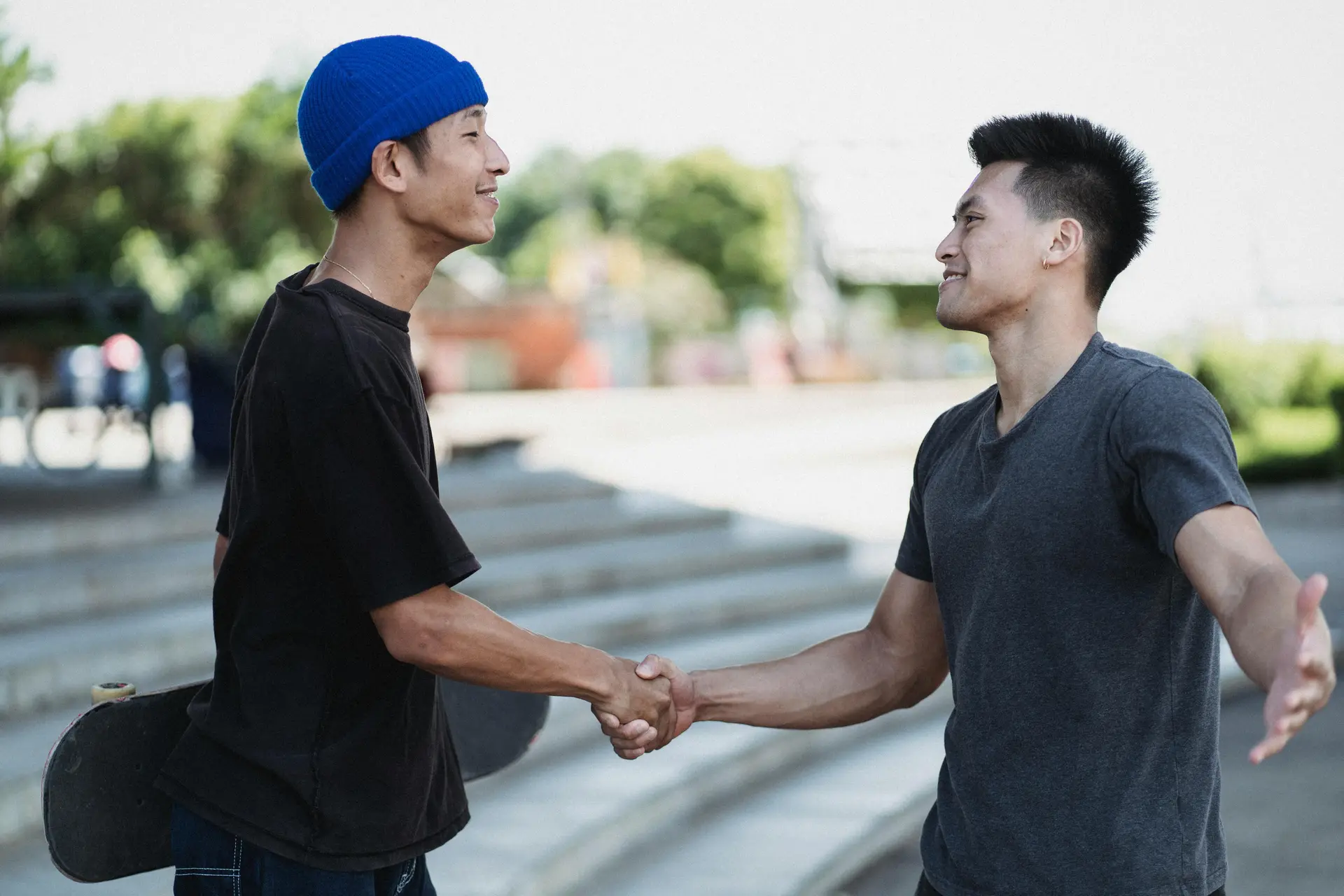 Two men shaking hand with each other. One is holding a skateboard.
