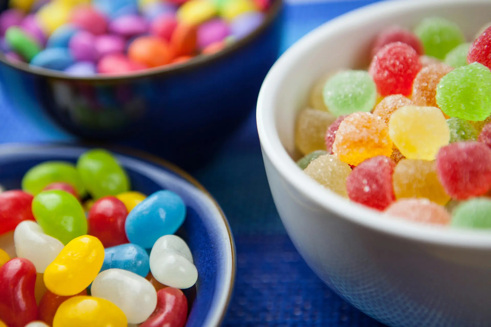 Three bowls filled with different types of candies.