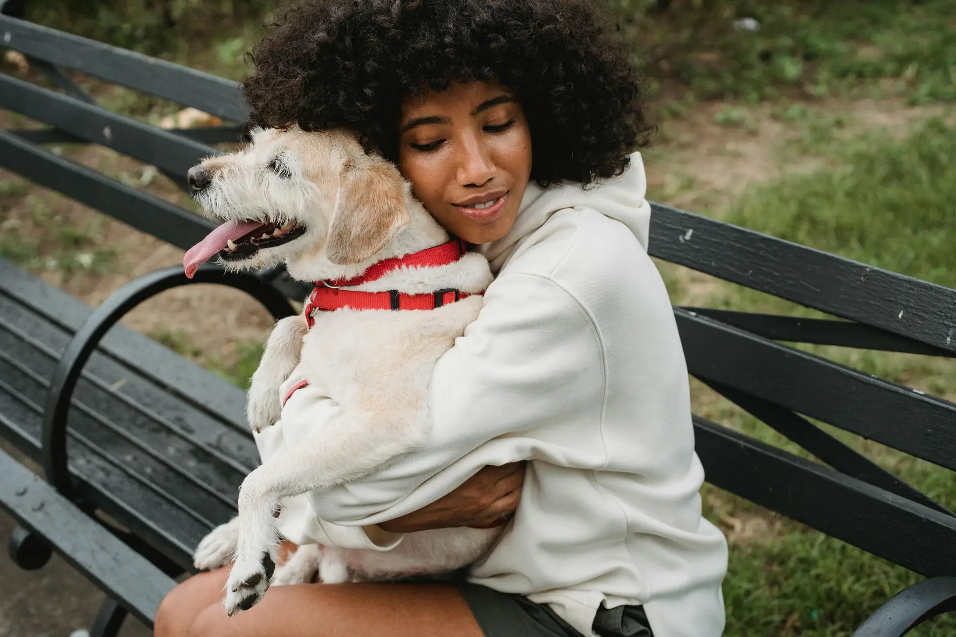 A women hugging a happy dog while sitting on a bench.