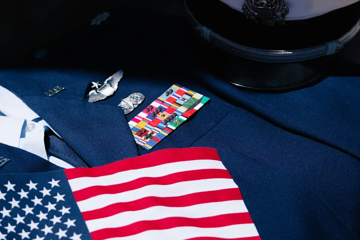 Close up of an american flag on a suit along with some other pins.
