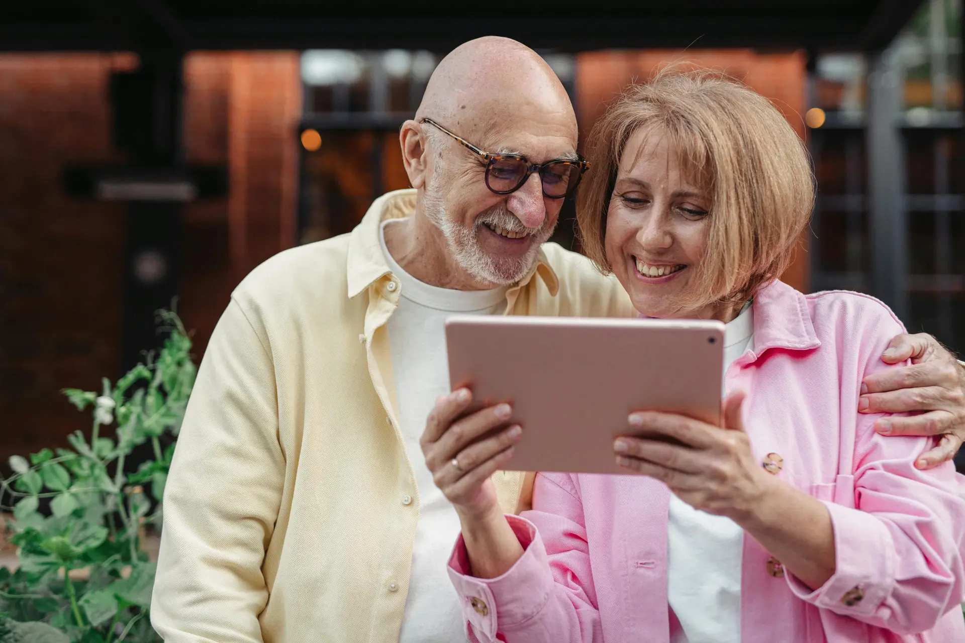 An elderly man watches a younger woman using tablet.