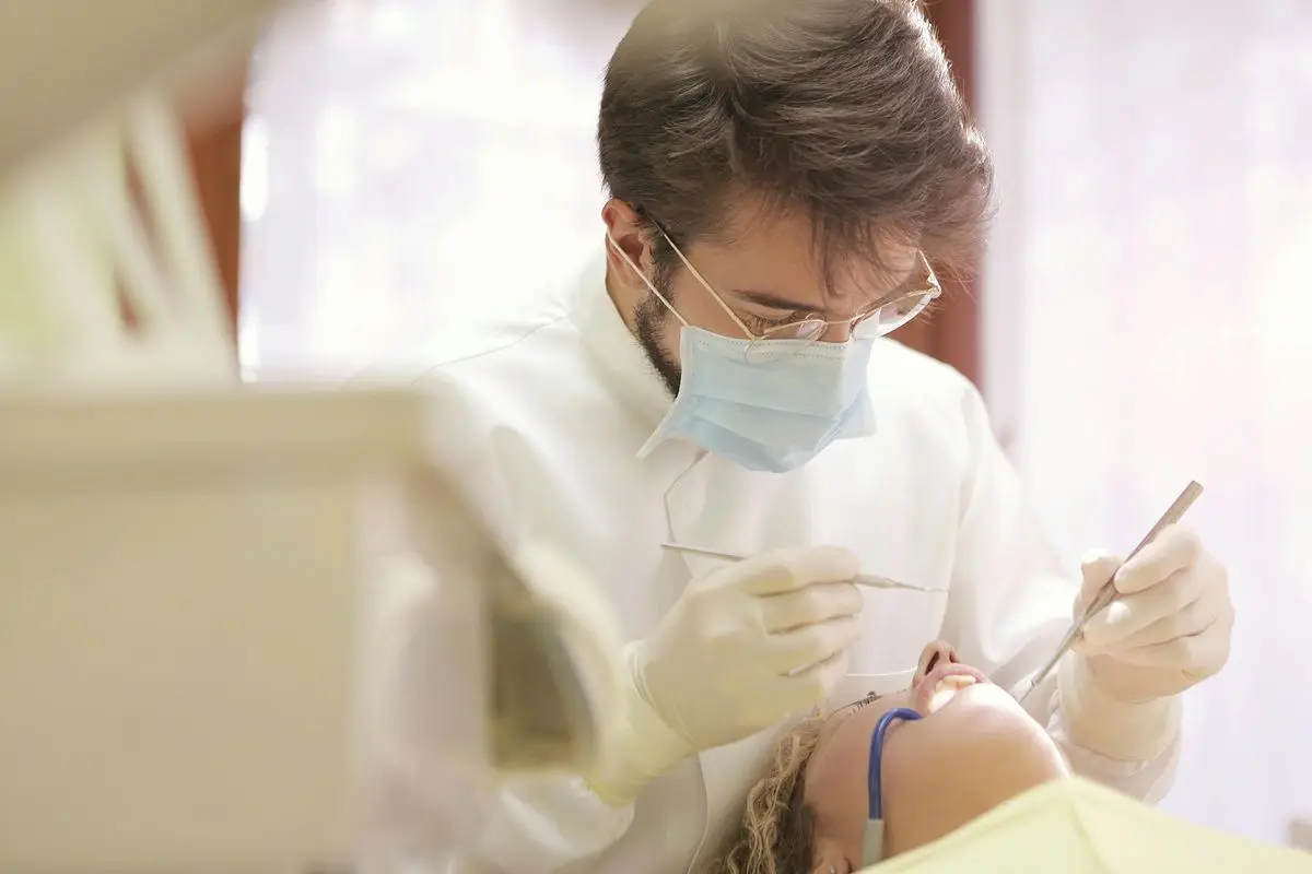 A dentist operating on a patient while wearing mask.