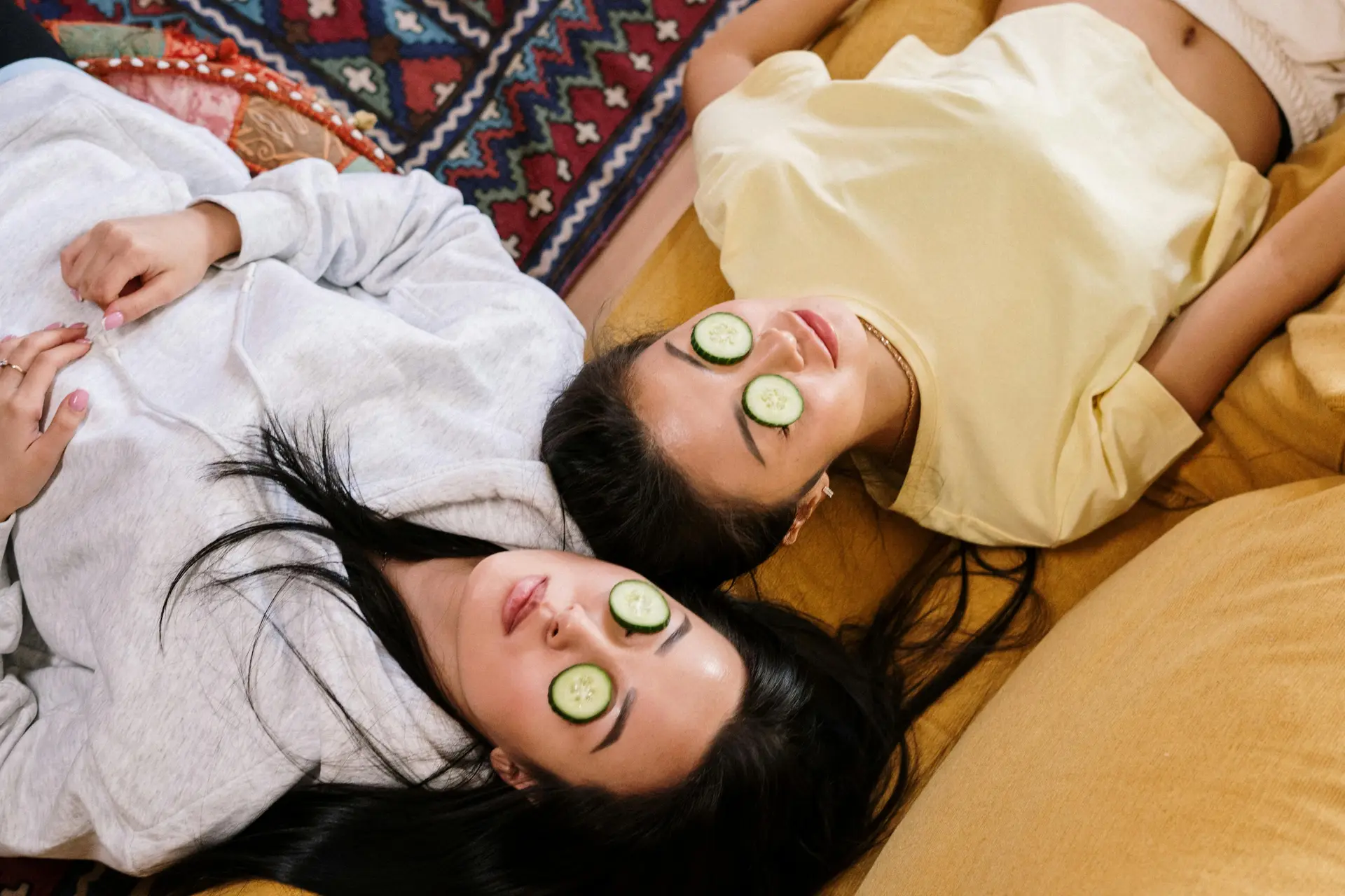 Two women enjoying spa at home. They both have cucumbers on their eyes.