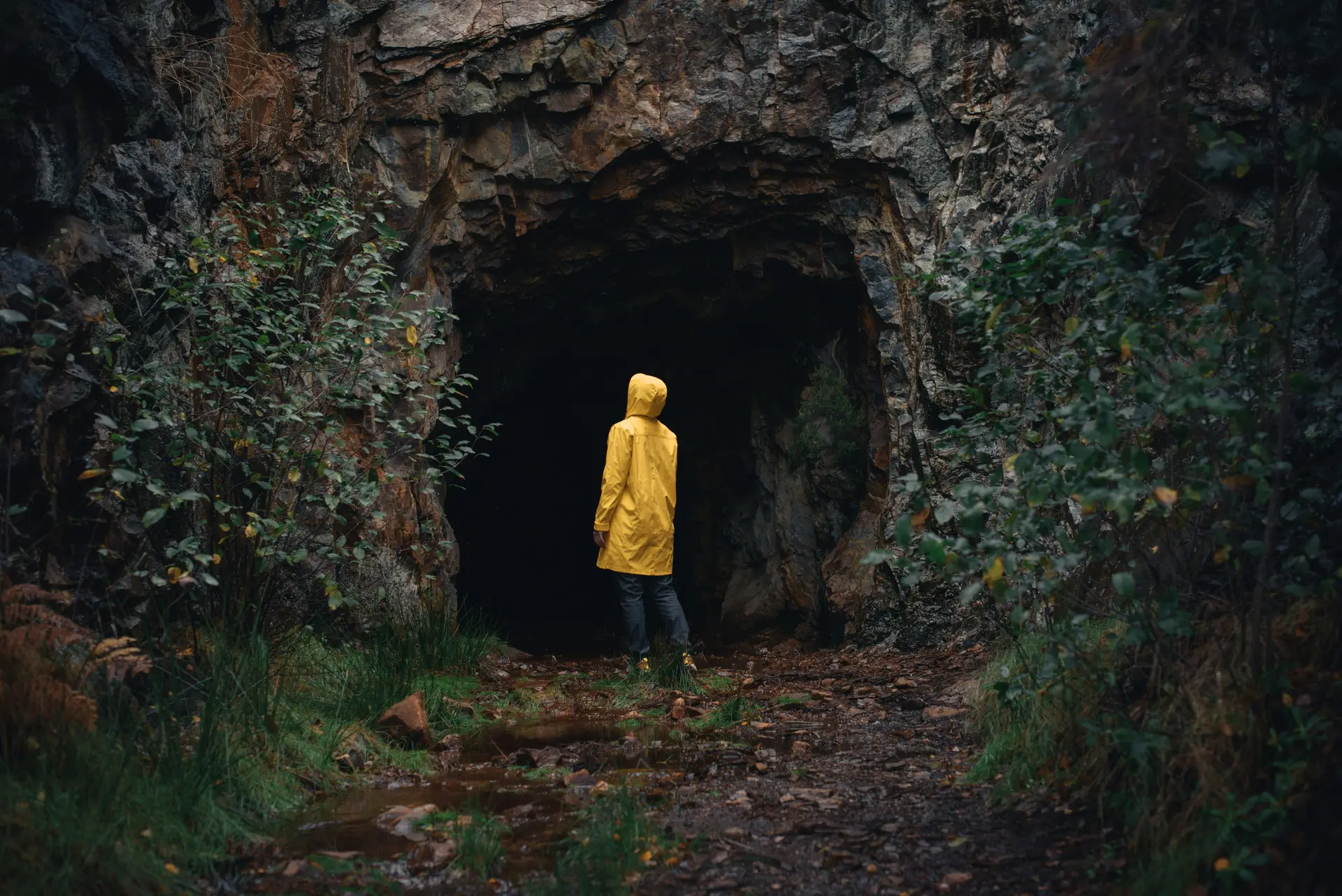 A person in a yellow jacket is standing in a cave.