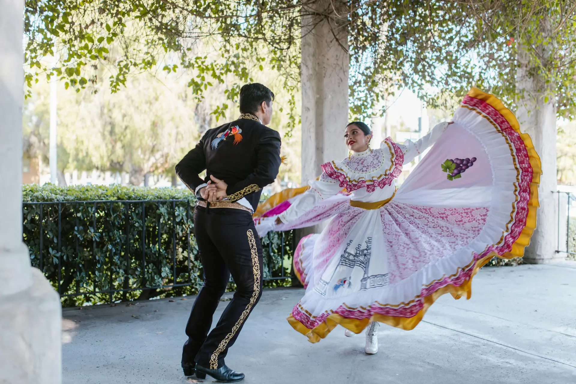 Man and a woman in traditional mexican clothes dancing together.