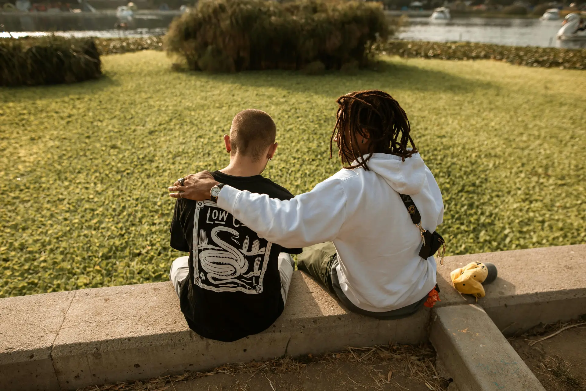 A man supporting his friend during talk by placing a hand over his shoulder.