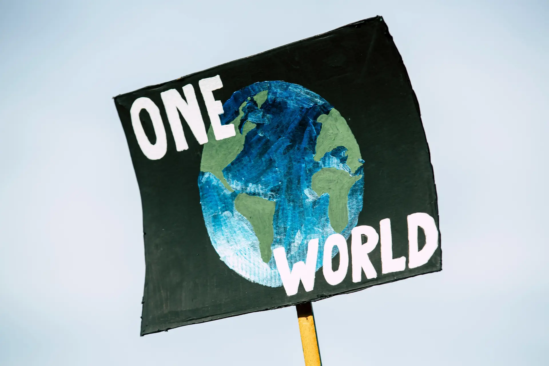A sign that says 'One World' and has the globe in the middle.