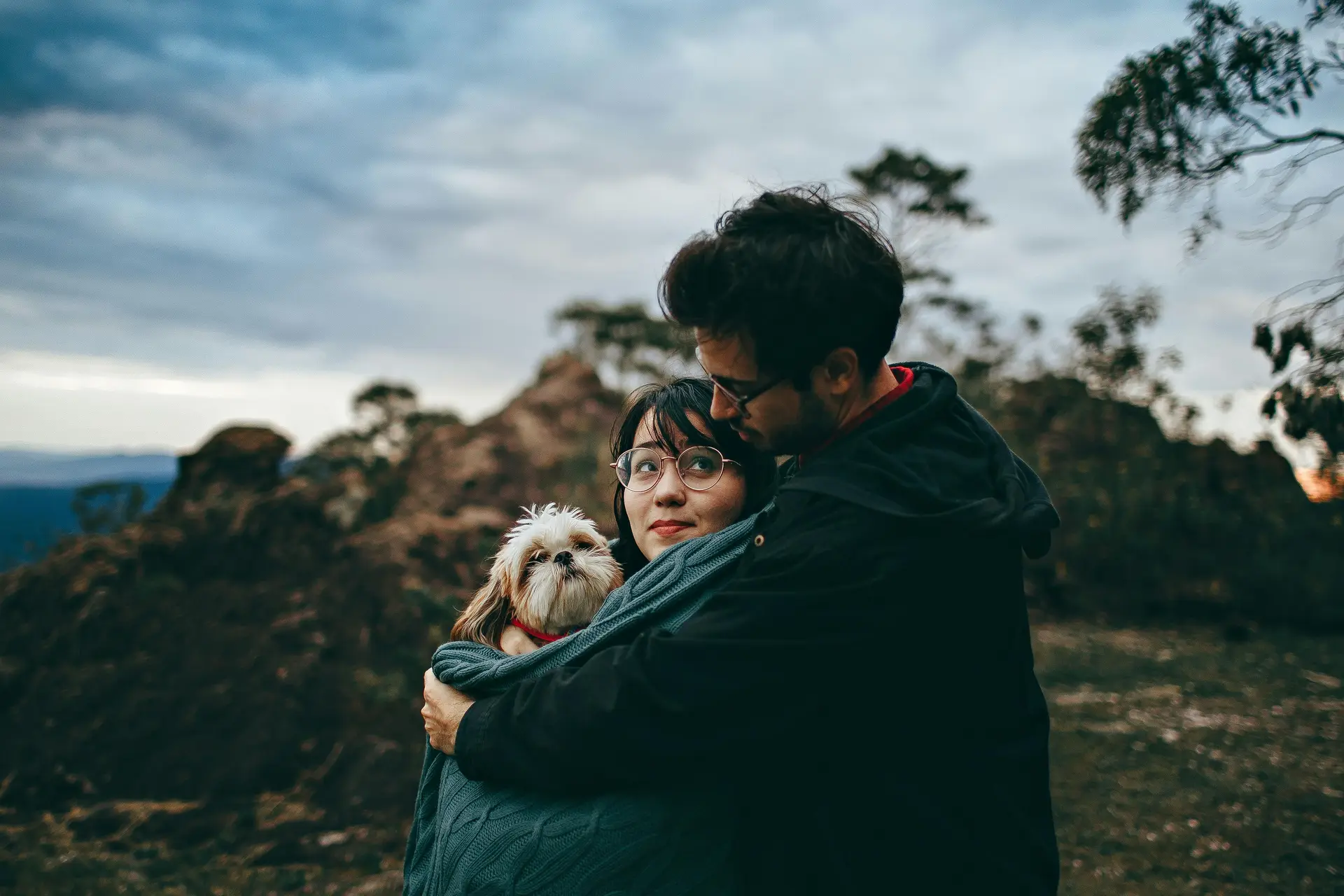 Boyfriend hugging his girlfriend and a dog in a scenic place.