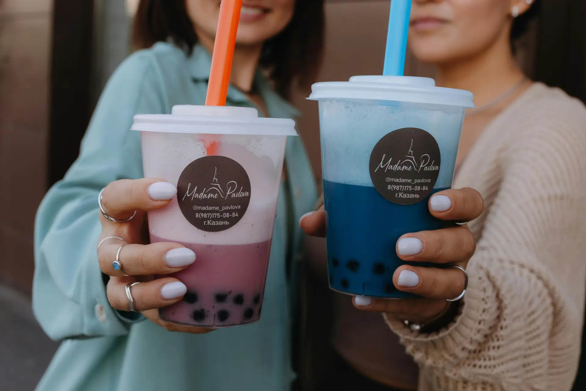 Two women holding two cups of tapioca drinks.