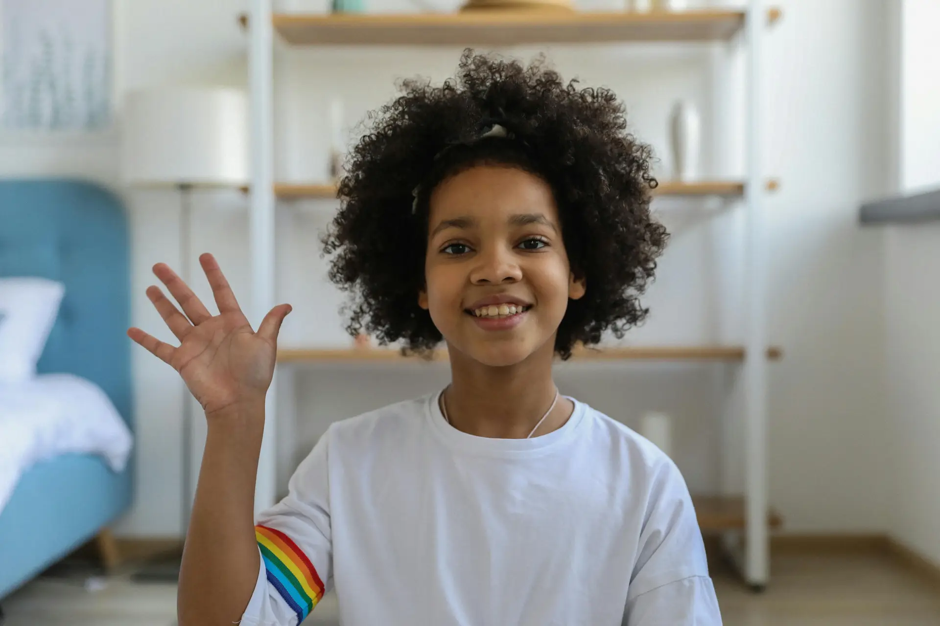 A kid saying hi as he waves his hand.