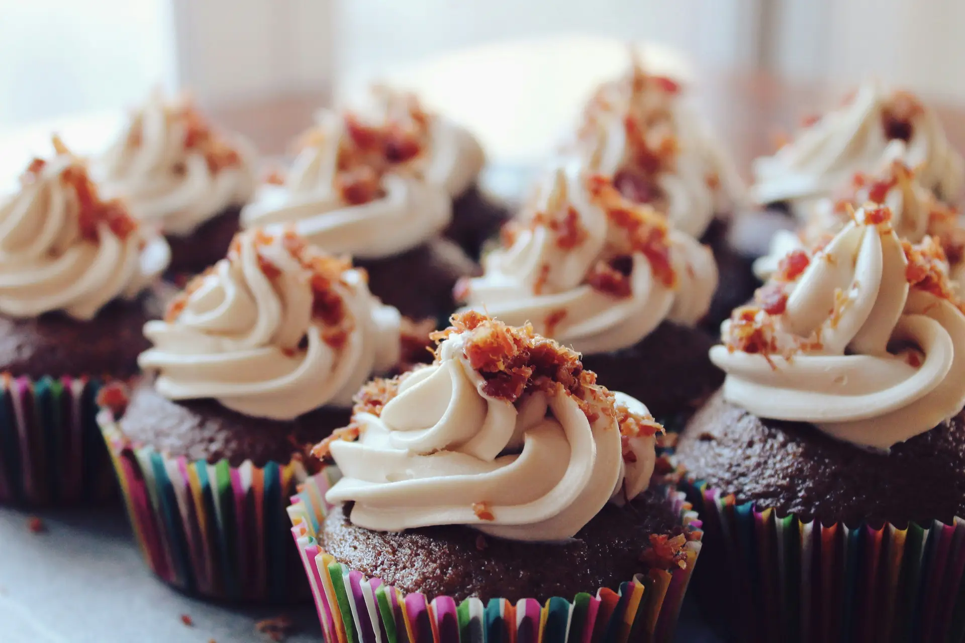 An assortment of chocolate cupcakes topped with whipped cream and sprinkles.