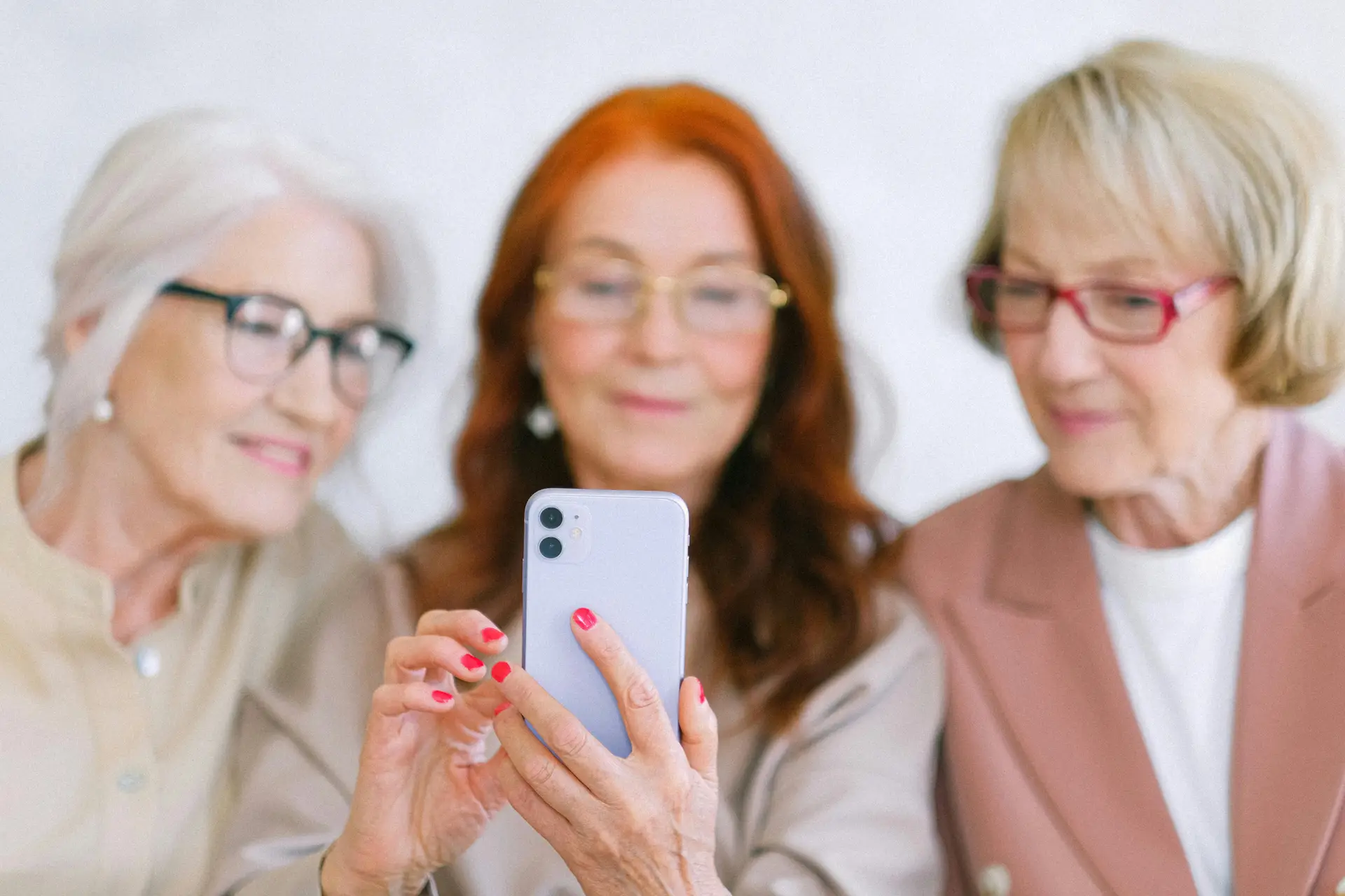A senior person using social media on her phone while other two people watch.