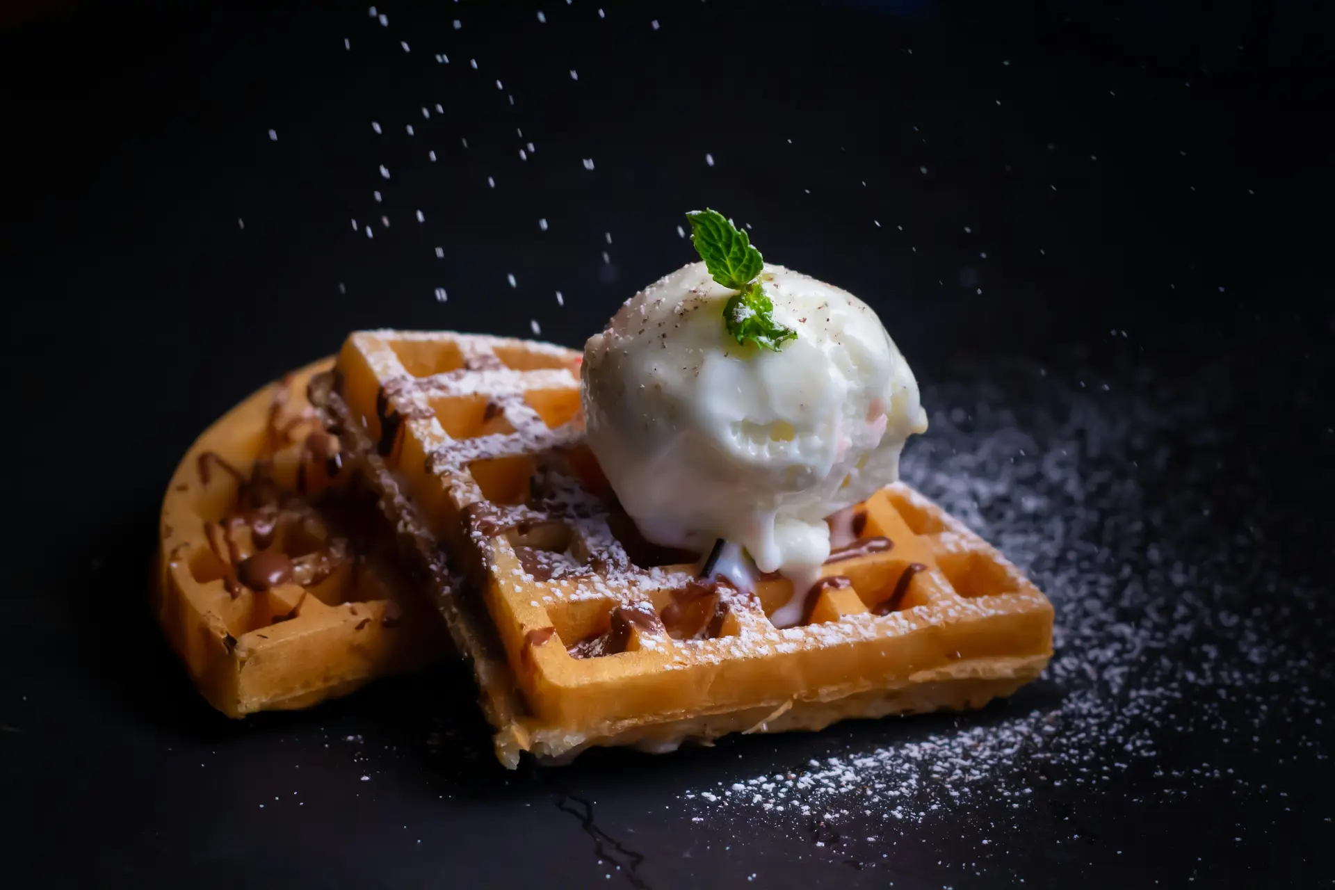 Two pieces of waffles with ice cream on top of them.