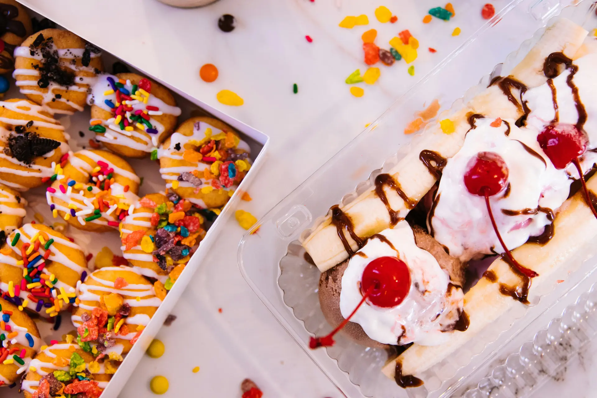 A banana split near some donuts.