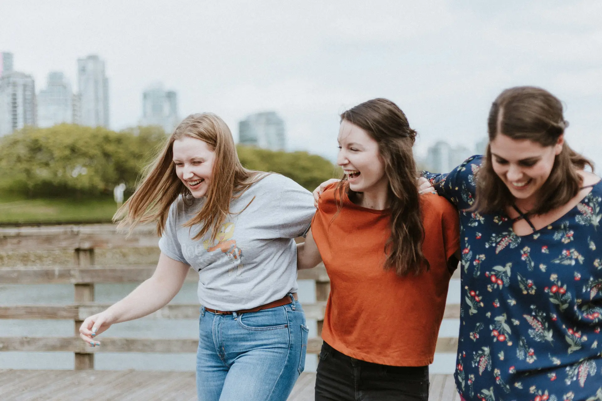 Three women laughing while walking.
