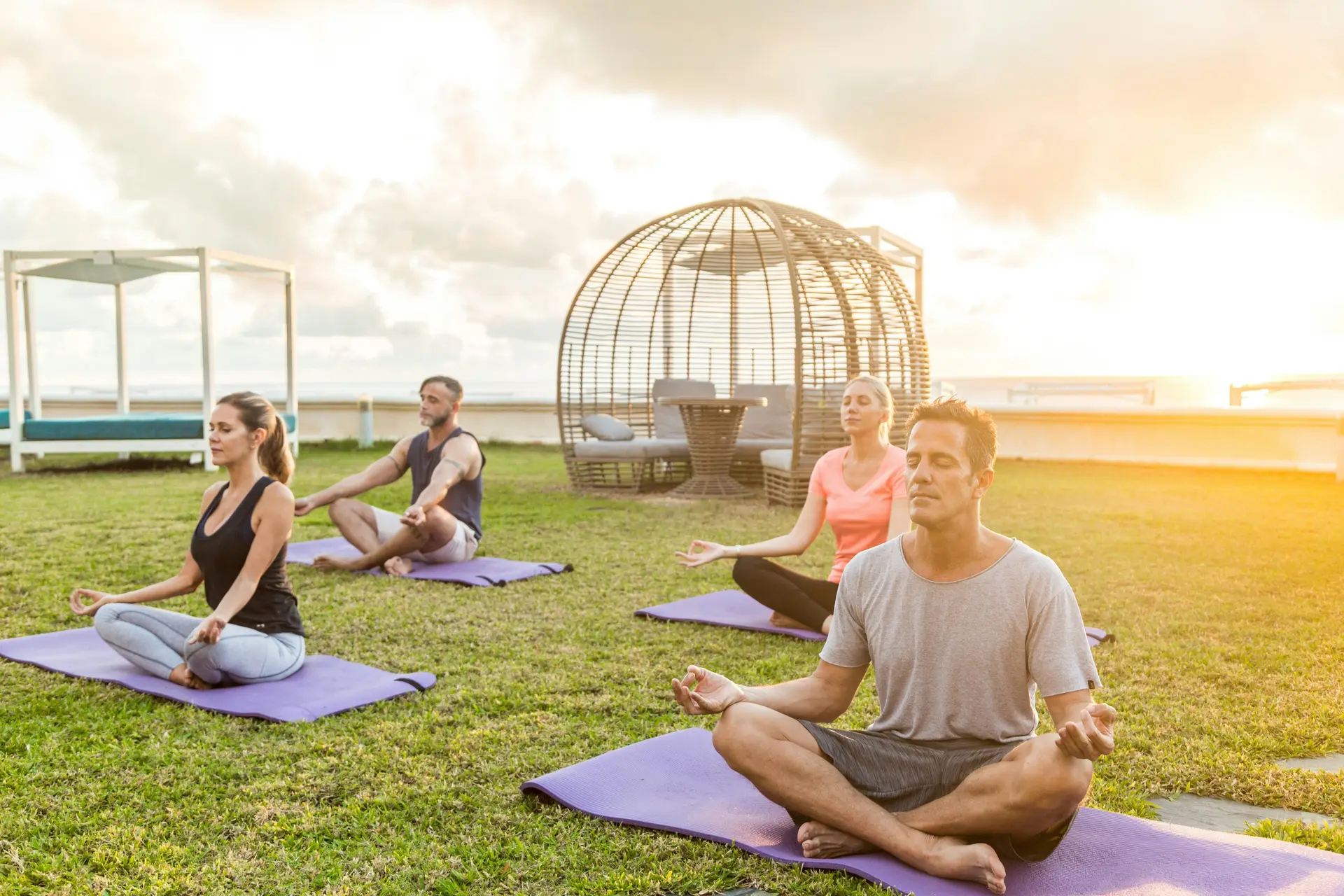 Bunch of people doing yoga outdoors on the grass.