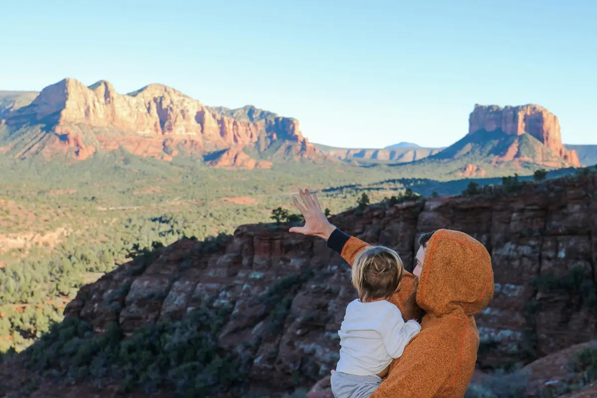 A person showing the mountain to a kid.