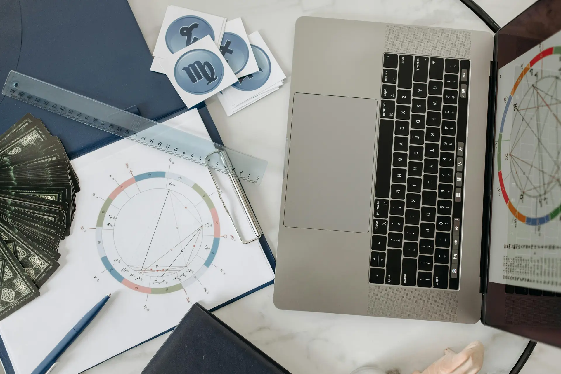 Birth chart, zodiac symbols, horoscope cards and an open laptop showing how to create a birth chart.