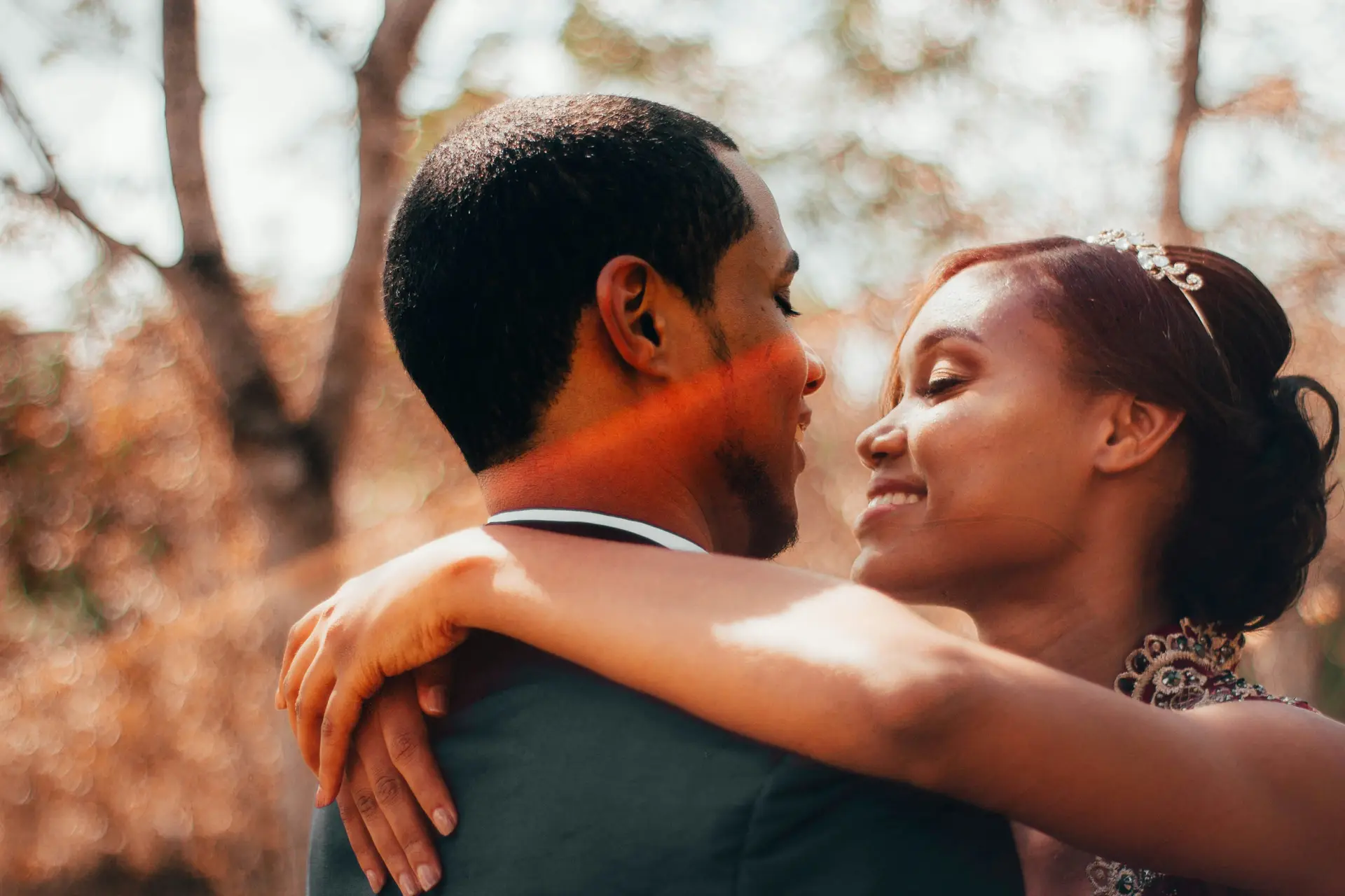 Black man hugging a black woman. They're about to kiss. as this is depicted as their wedding.