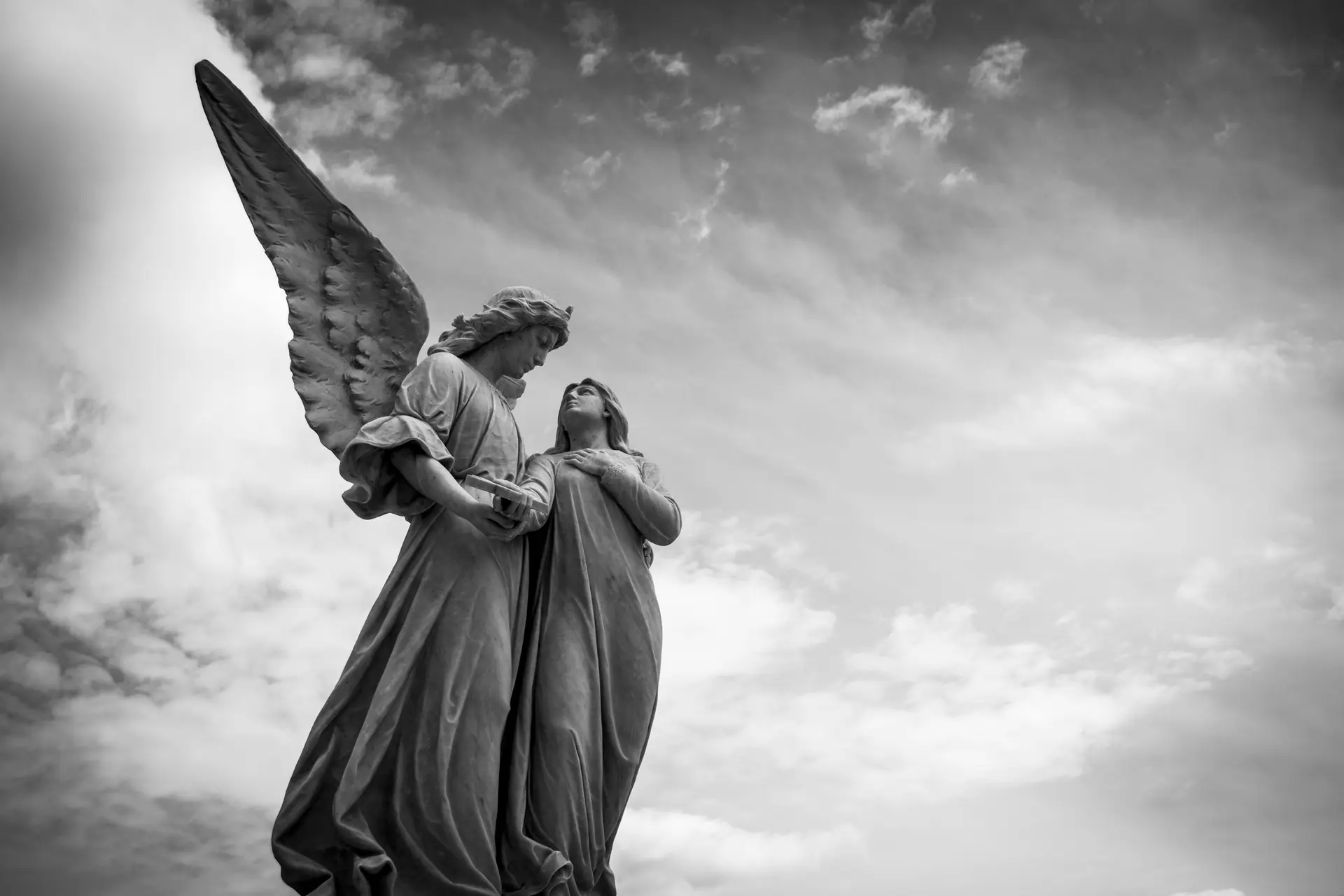 An angel statue holding a girl statue.