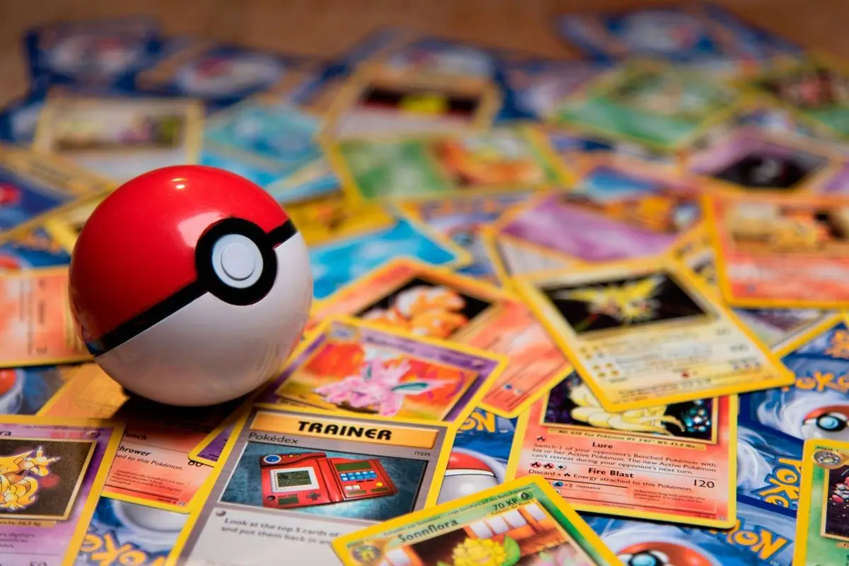 A red and white pokeball on a bunch of pokemon cards.