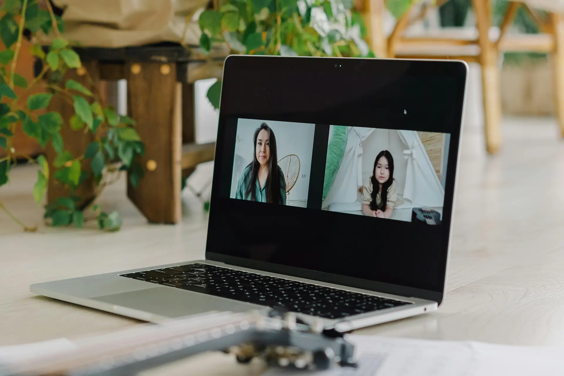 A laptop on a wooden surface, displaying a video call between two women.