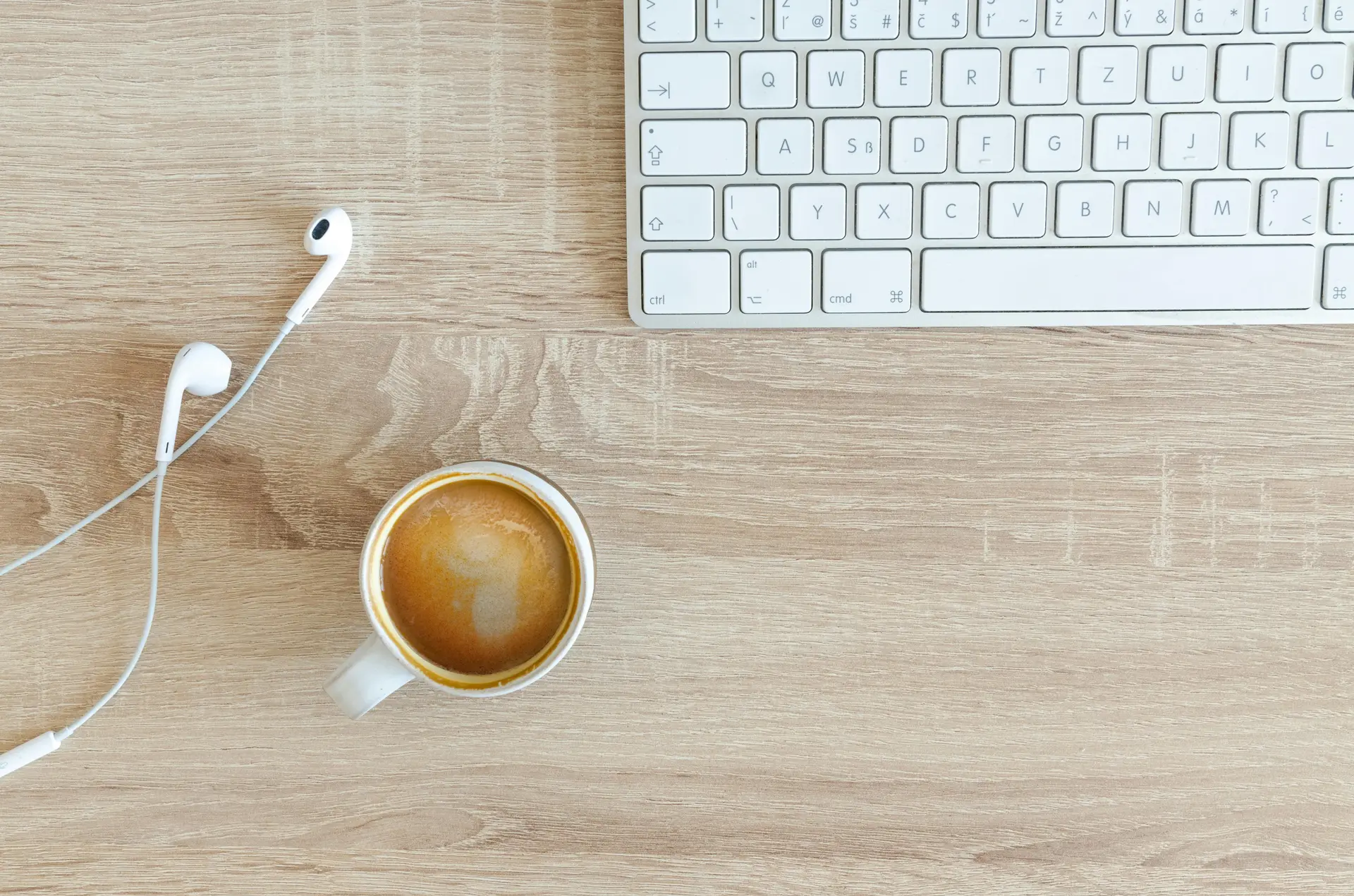 Coffee Filled Mug Near Apple Airpods With Lightning Connector and Apple Magic Keyboard
