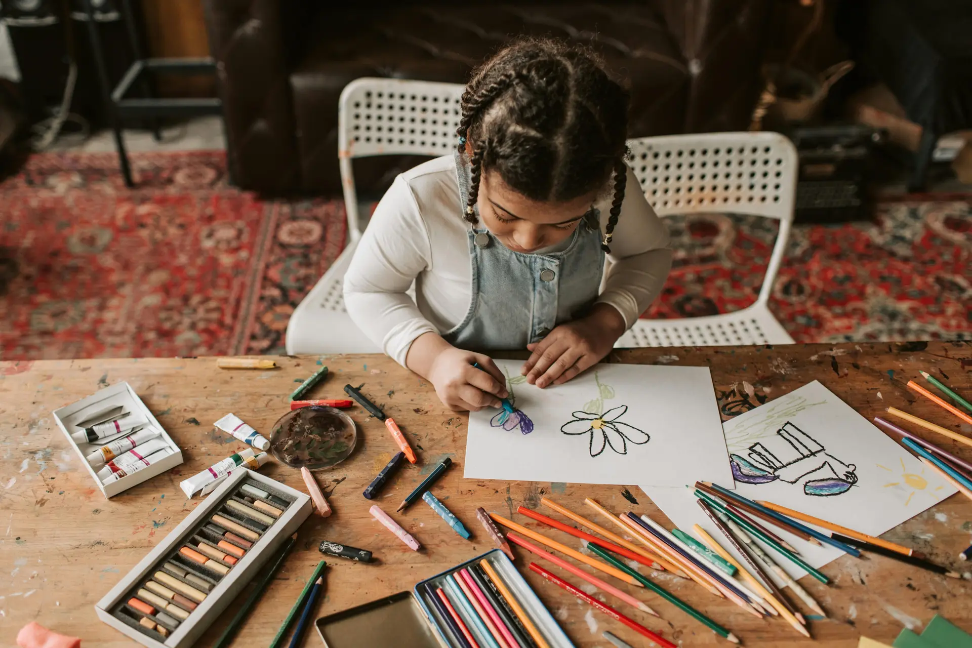 A girl drawing on paper with pencils.