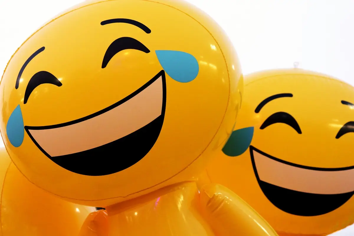 A couple of balloons that have emoji faces on them.