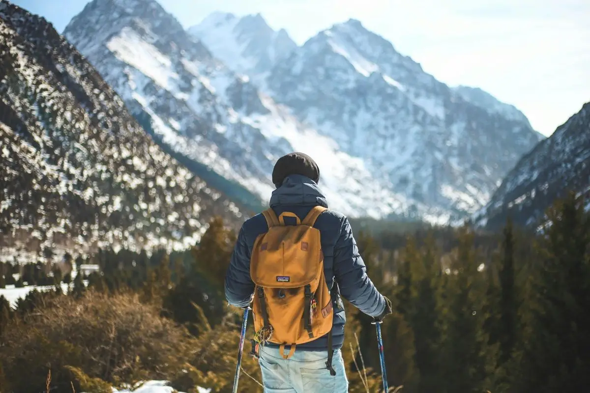 A man is standing in front of a mountain, the view is beautiful.