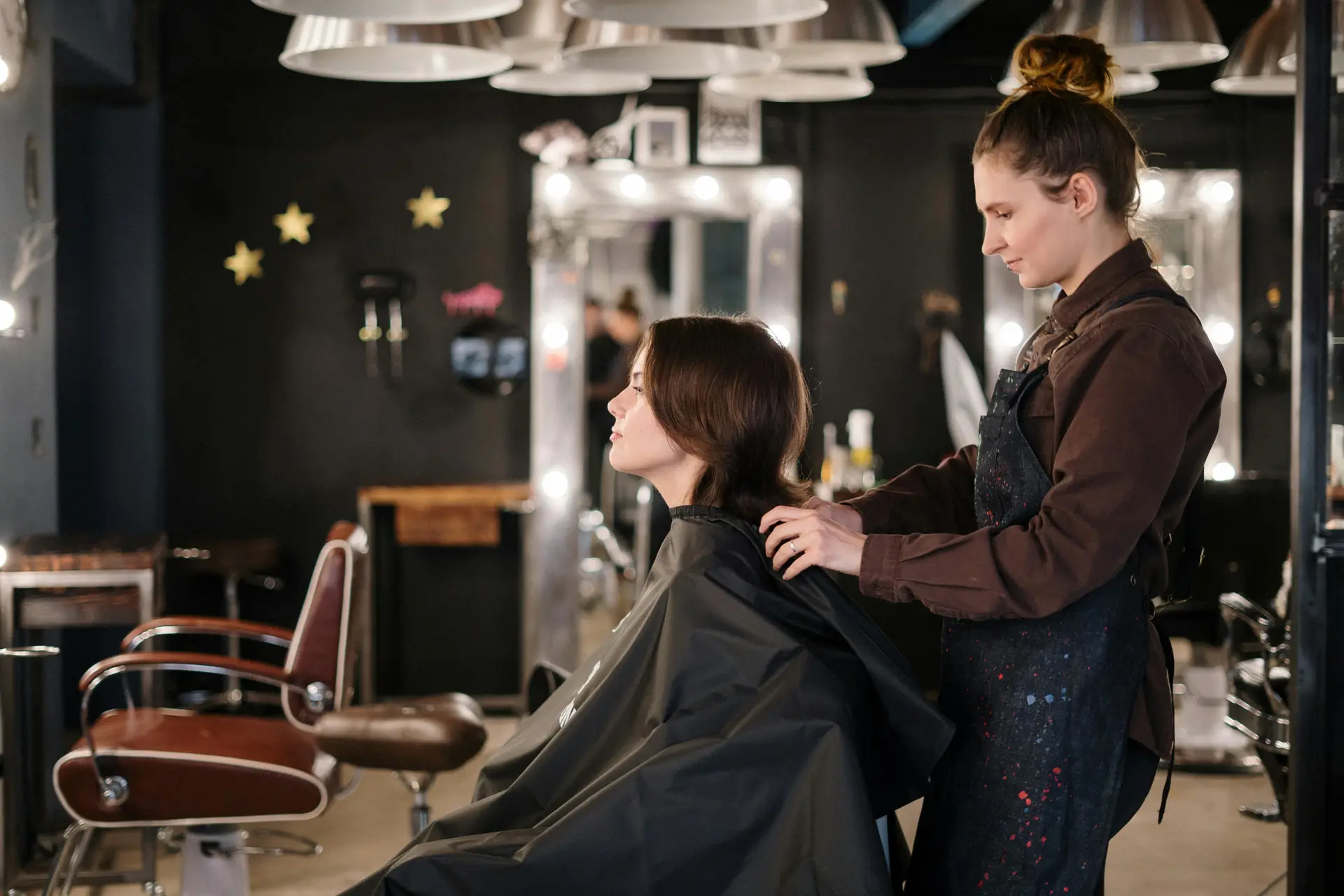 A women hairstylist cutting hair of another women in a saloon.
