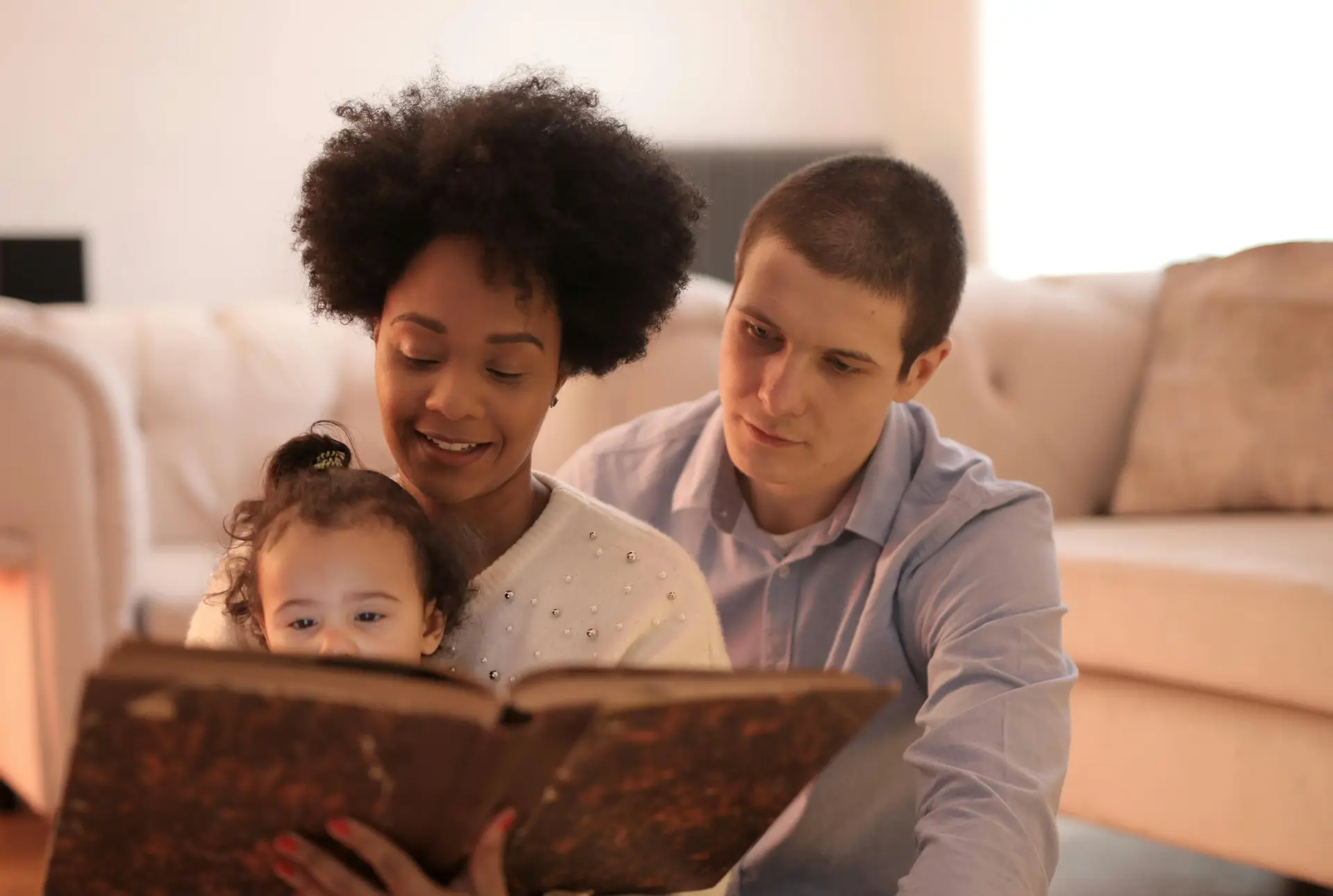 Father, mother, and child reading a book together.