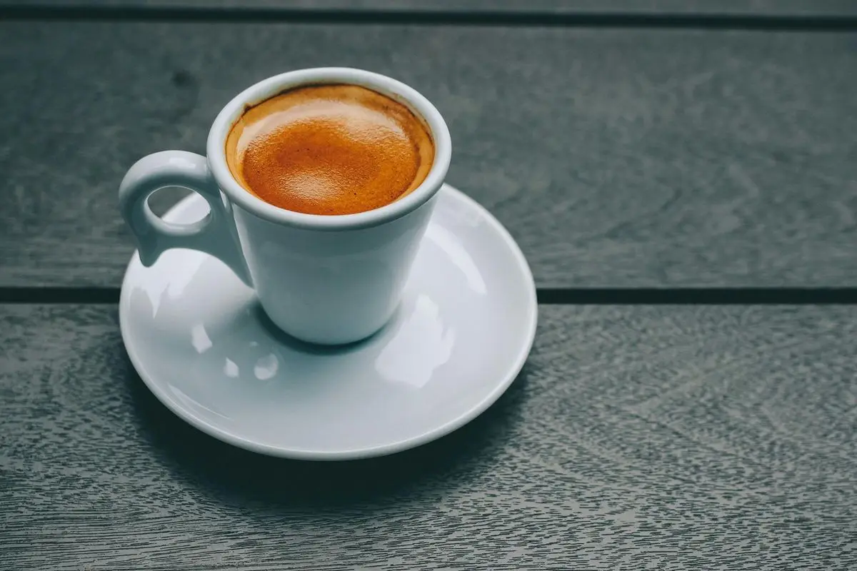 A fresh cup of Espresso is placed on a wooden surface.
