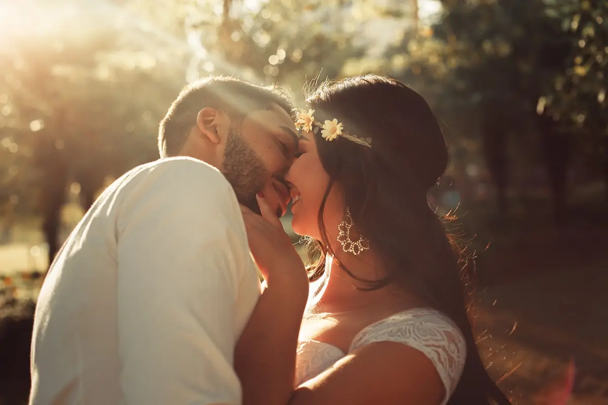 A romantic outdoor wedding couple sharing an intimate moment at sunset.