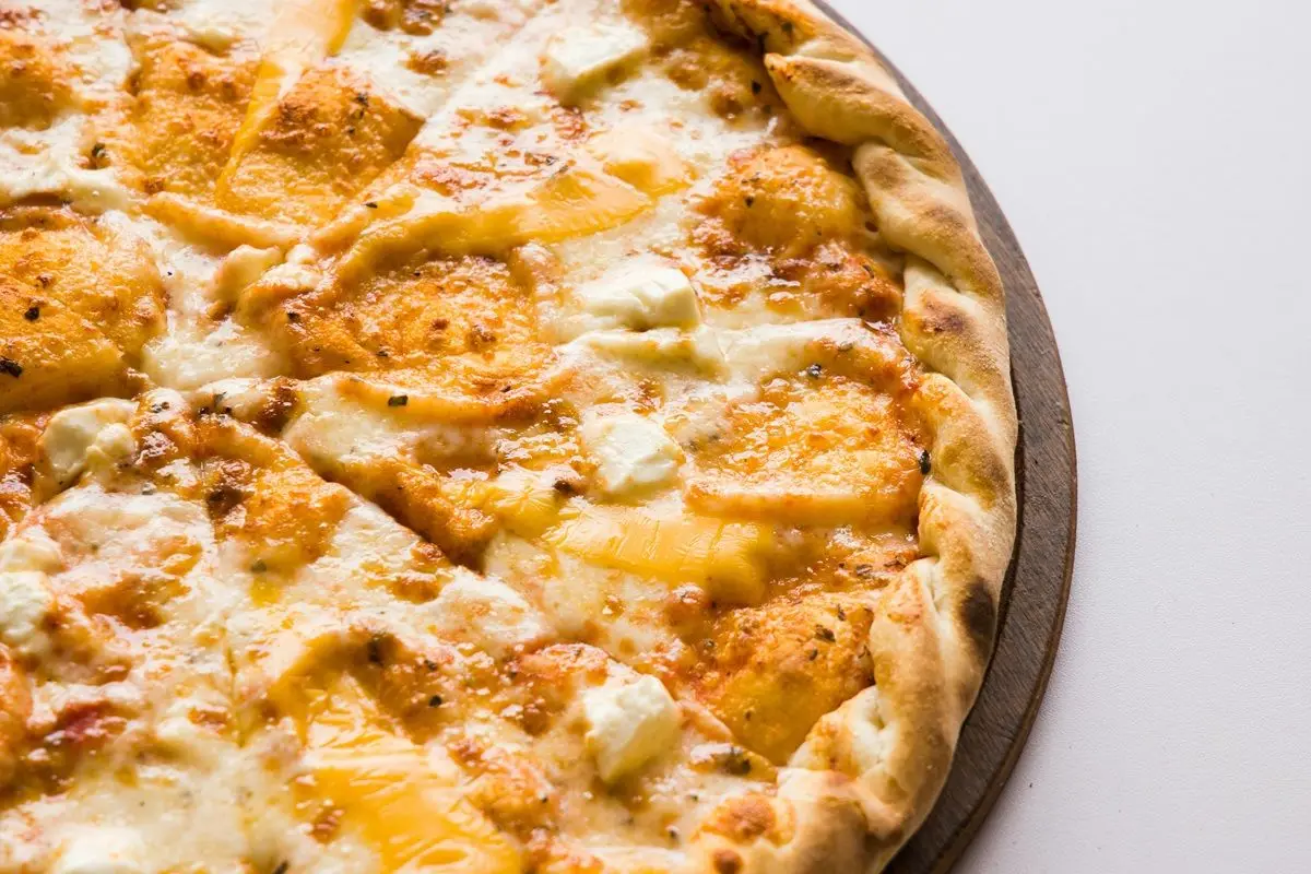 Baked cheese pizza on a white surface.