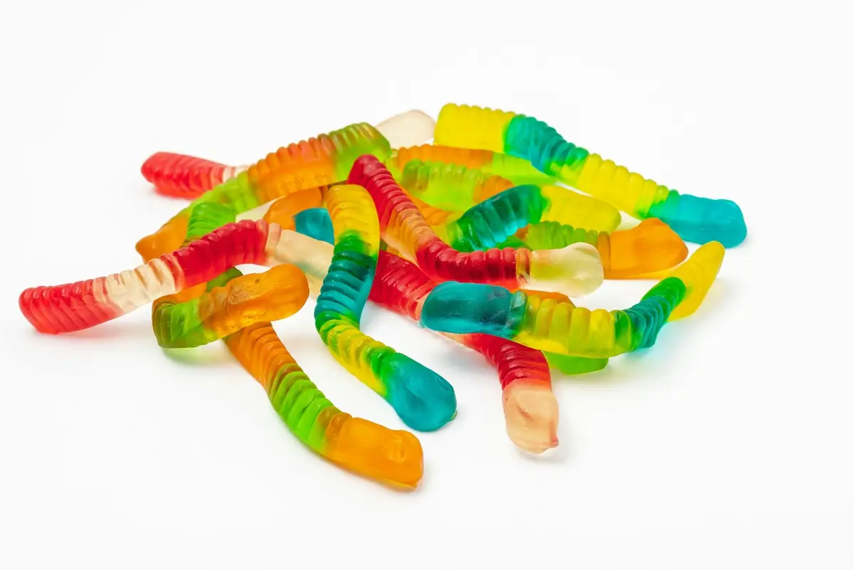 Bunch of gummi worms on a white surface.