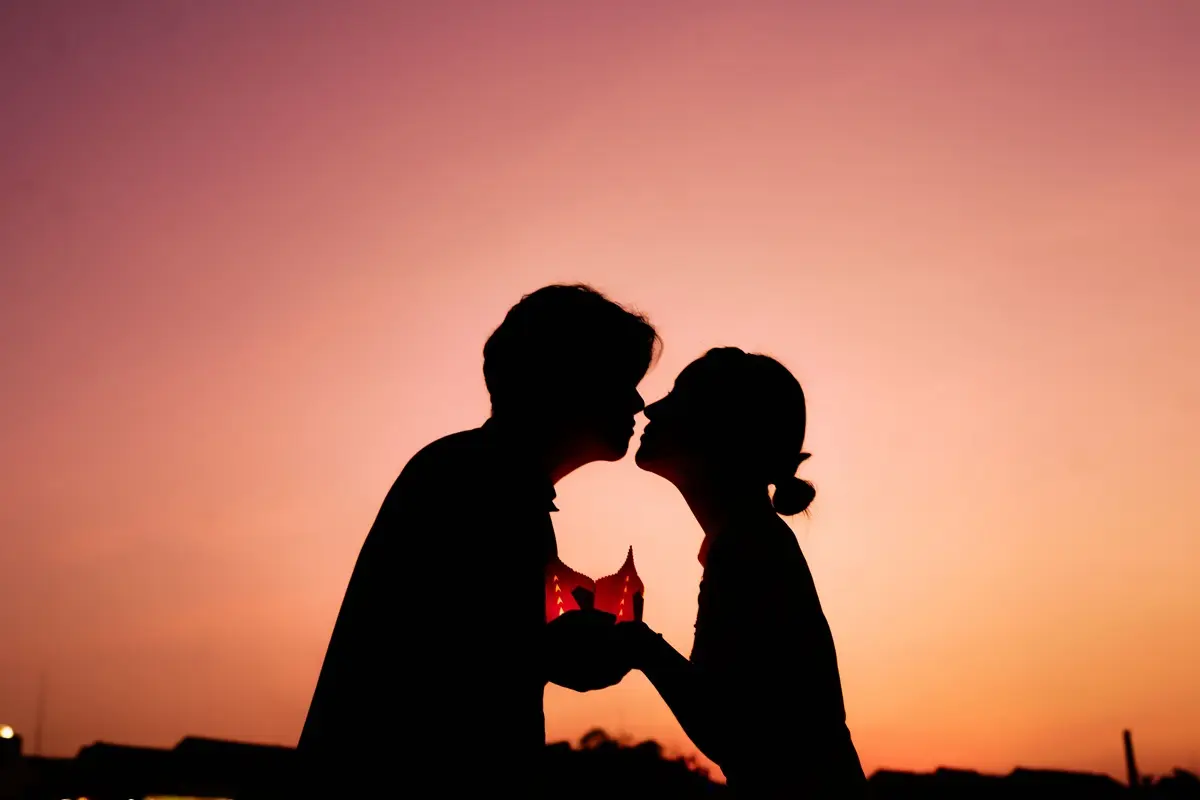 Silhouette of a couple kissing against a beautiful sunset, symbolizing love and affection.