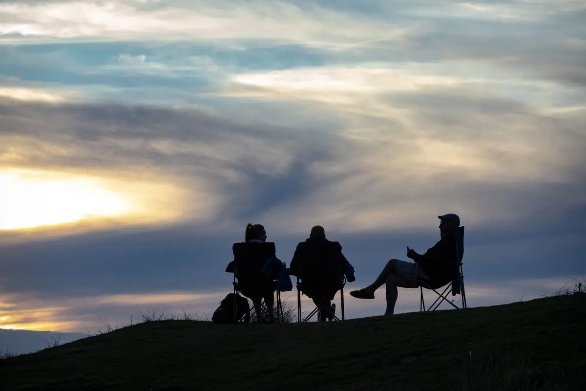 Silhouetted group enjoying the twilight hour under a dramatic sky.