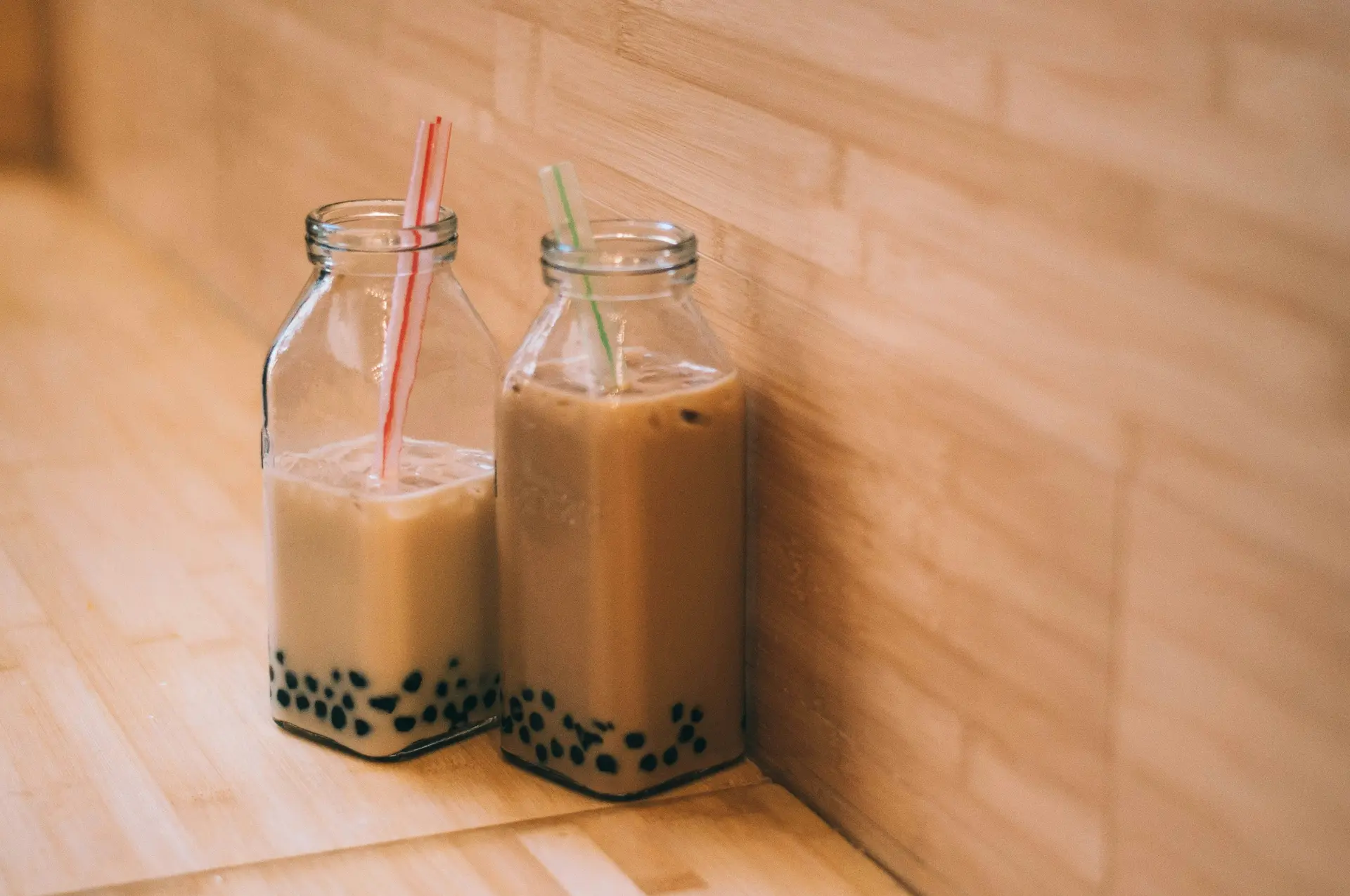 Two clear glass jars with straws and in them is bubble tea.