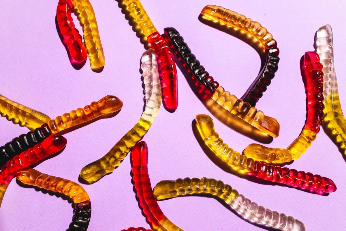colorful gummy worms scattered on a vibrant purple surface