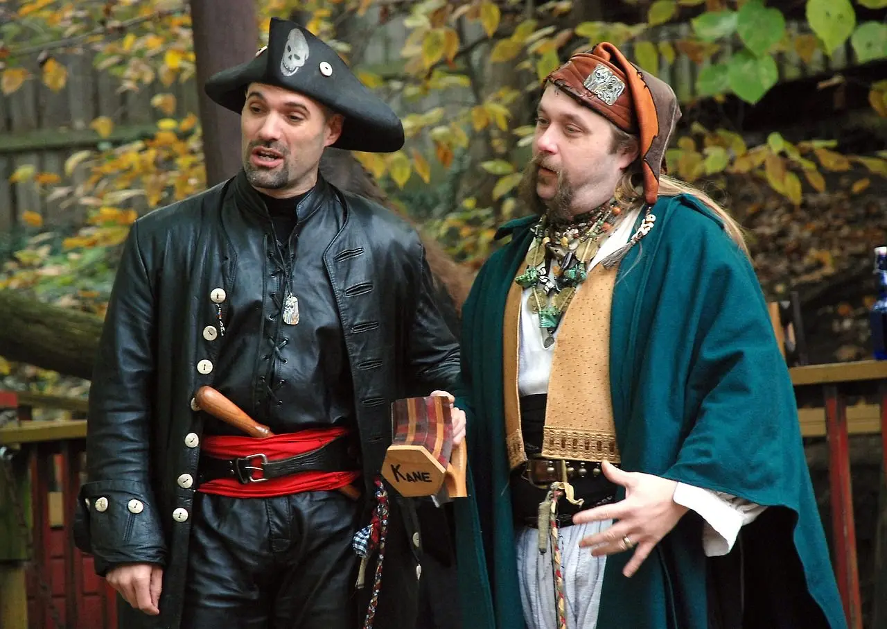 Two person wearing pirates costume talking to each other.