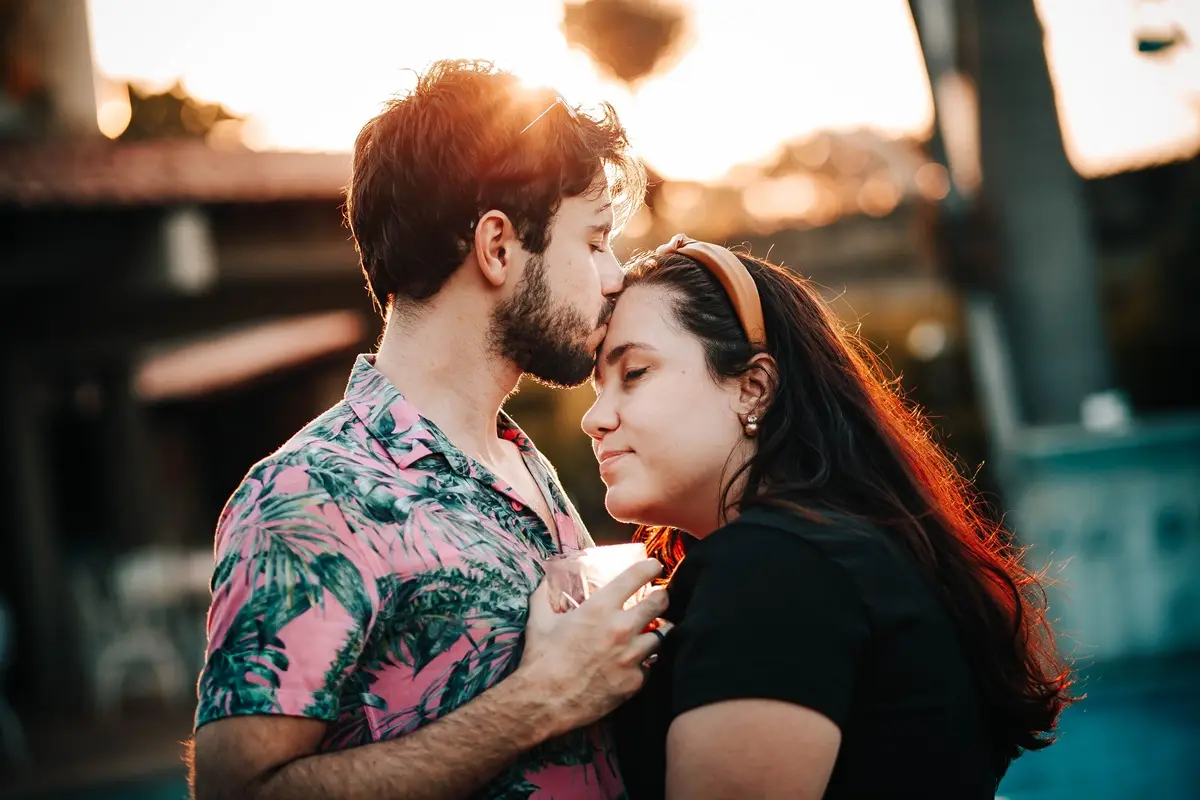 A loving couple shares a tender moment outdoors during sunset, symbolizing affection and togetherness.